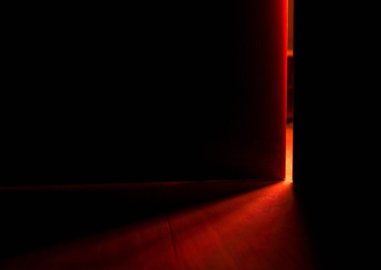 A dark bedroom with light coming in through a slightly open door at Blind Corners near Roseville, CA